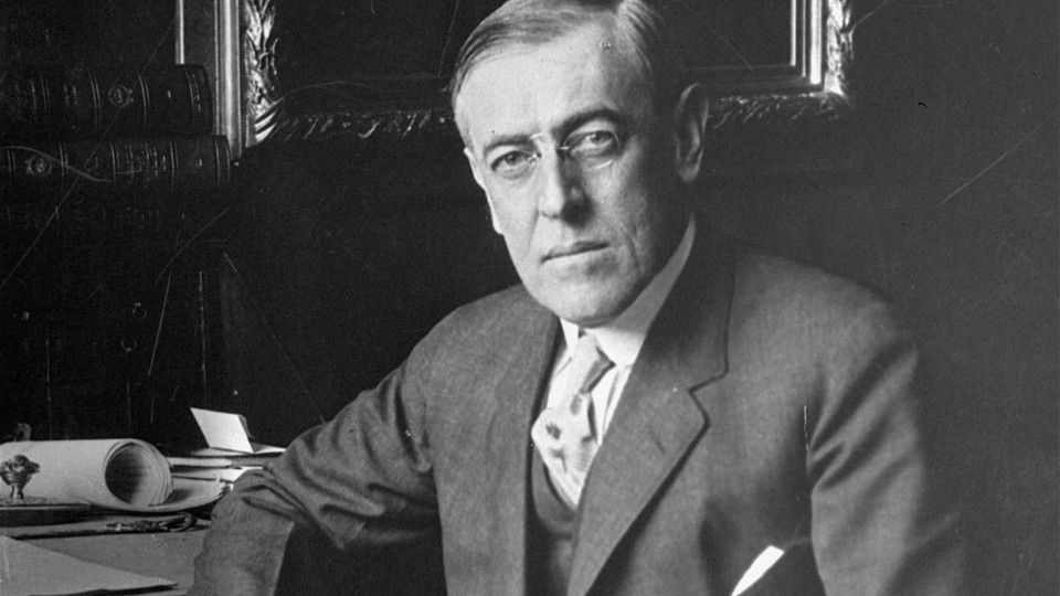 An archival photo of Woodrow Wilson sitting at a desk