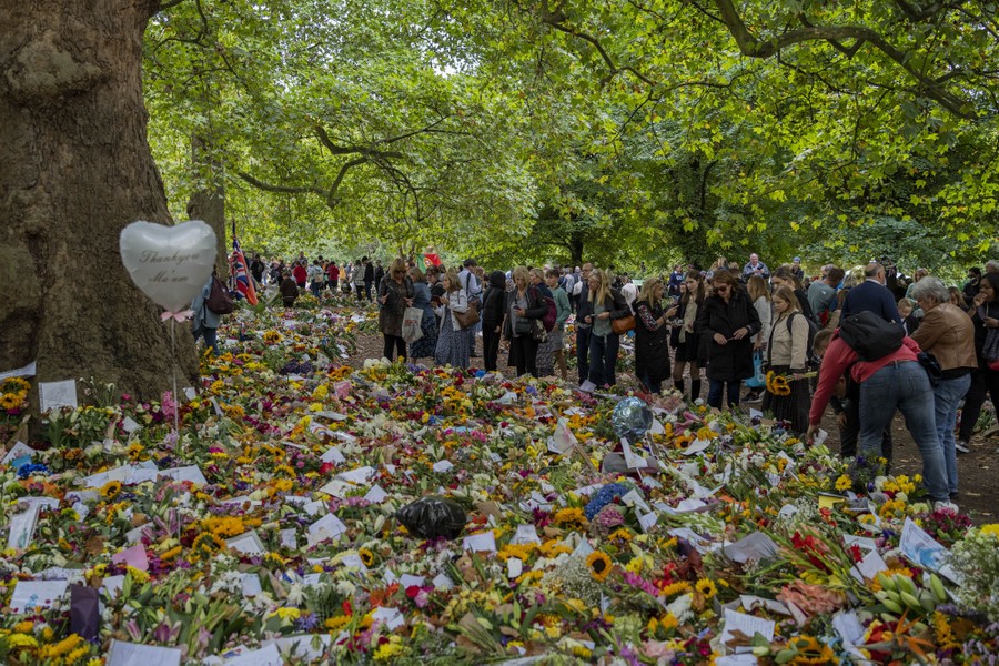 A crowd looks at a huge pile of flower bouquets.