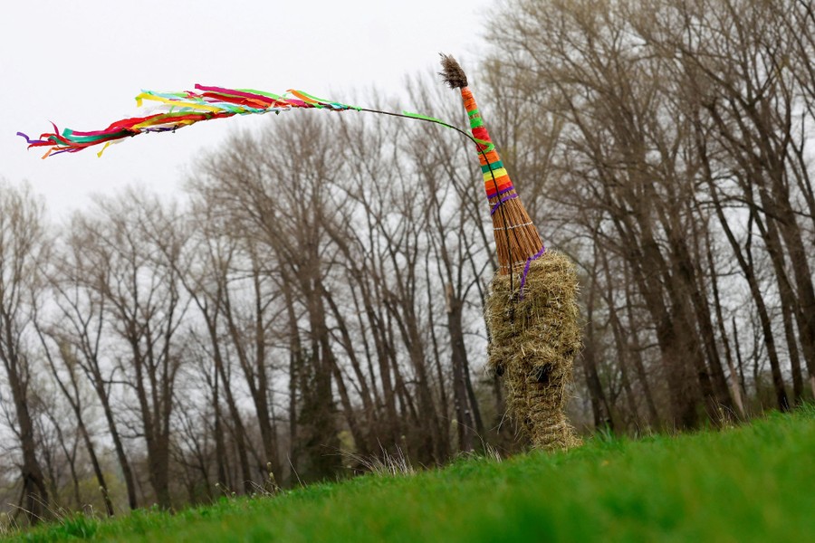 A boy dressed in a costume made of hay and colorful ribbons walks through a field