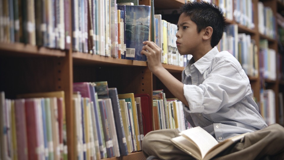 A boy looks through the shelves at a library.