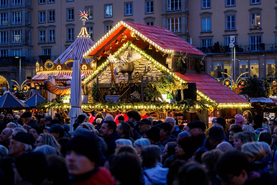 A crowd moves about in a Christmas marketplace.
