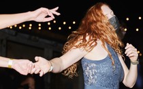 A woman dances at a party while wearing a mask