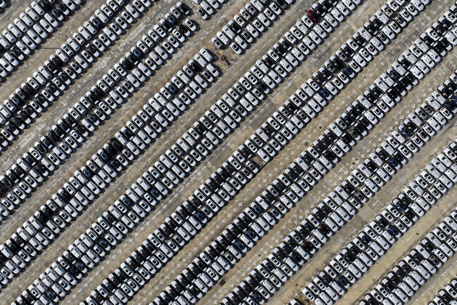 Hundreds of new cars are lined up in a parking lot.