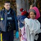 RCMP officer looks on as a woman carrying a child waits to cross the U.S.-Canada border.