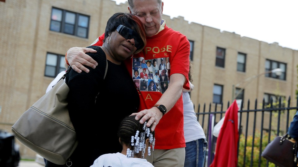 Michael Pfleger, a Chicago priest and voice in the anti-violence movement in the city, comforts the family of a shooting victim earlier this year.