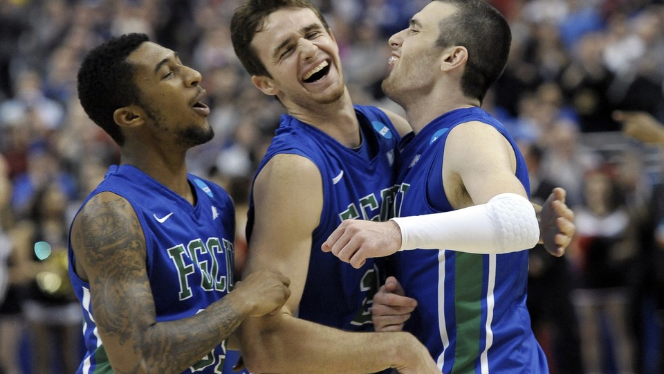 Three basketball players hug and smile