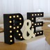 A decoration featuring a couple's initials sits on a table at a wedding reception.