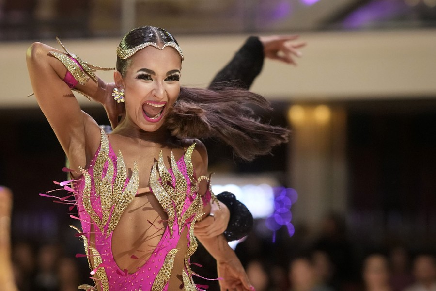 A ballroom dancer wearing a colorful costume smiles while performing.