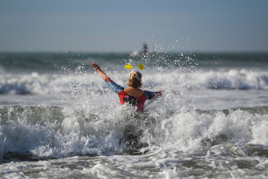 A woman wearing stars on her head plunges into the surf.