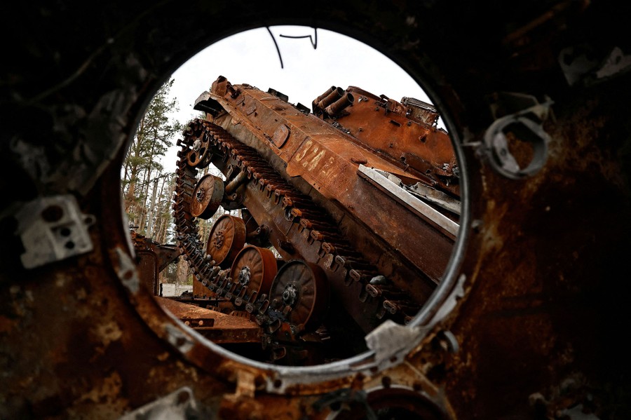 Several destroyed tanks framed by a hole in another damaged vehicle