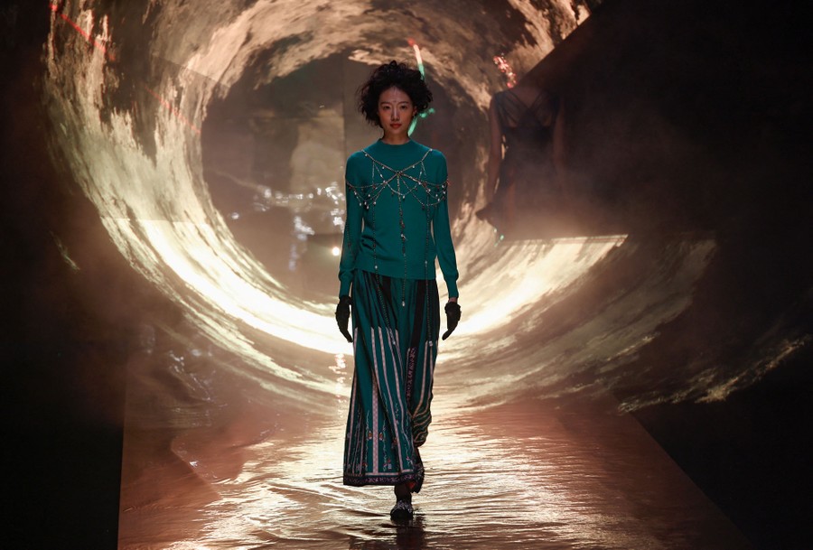 A model walks on a runway, surrounded by a circle of light.