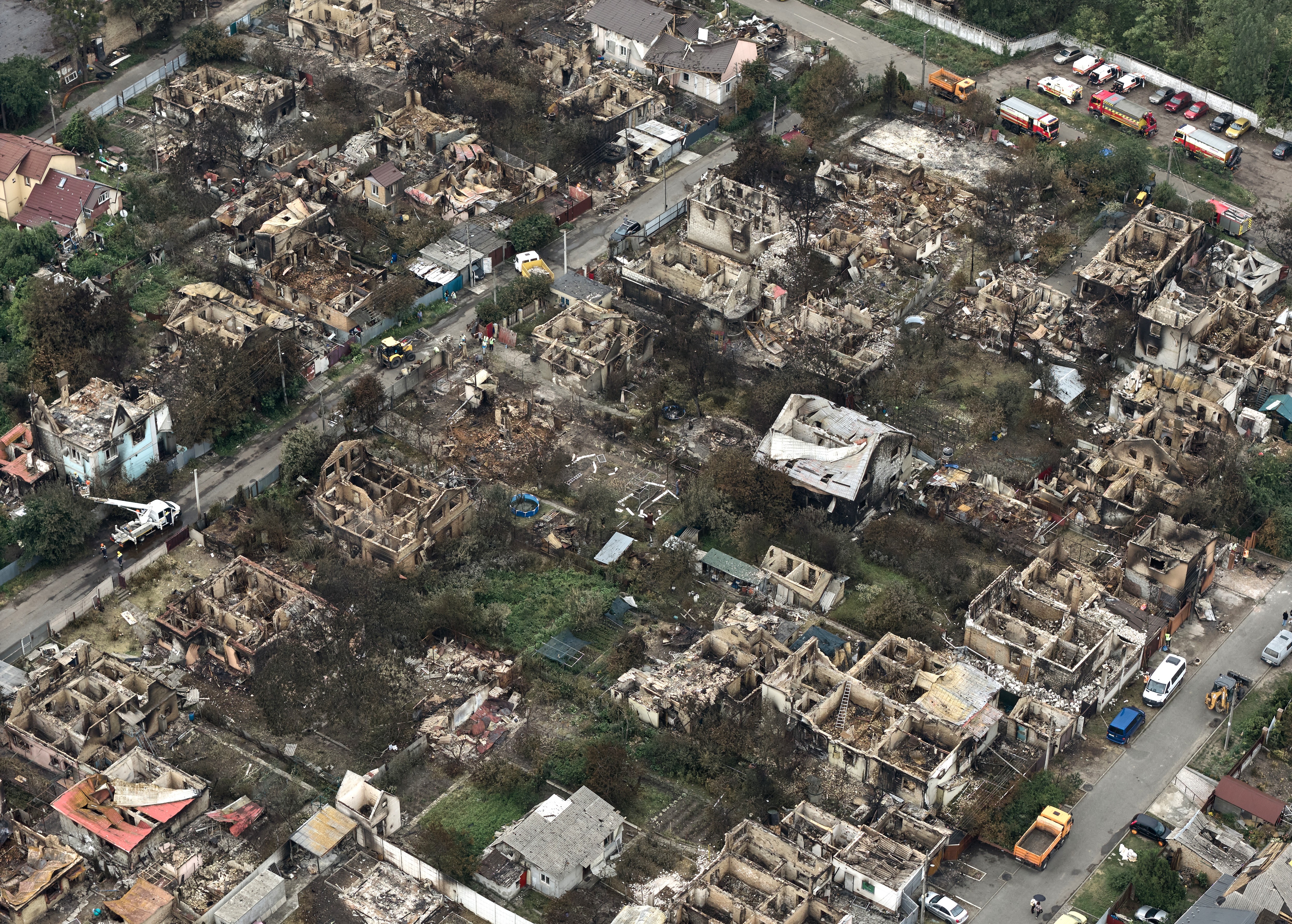 An aerial view of burned-down houses and damaged streets in a residential neighborhood
