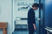 Jeremy Allen White as Carmy rests his head against the door of a walk-in freezer in a scene from Season 3 of "The Bear."