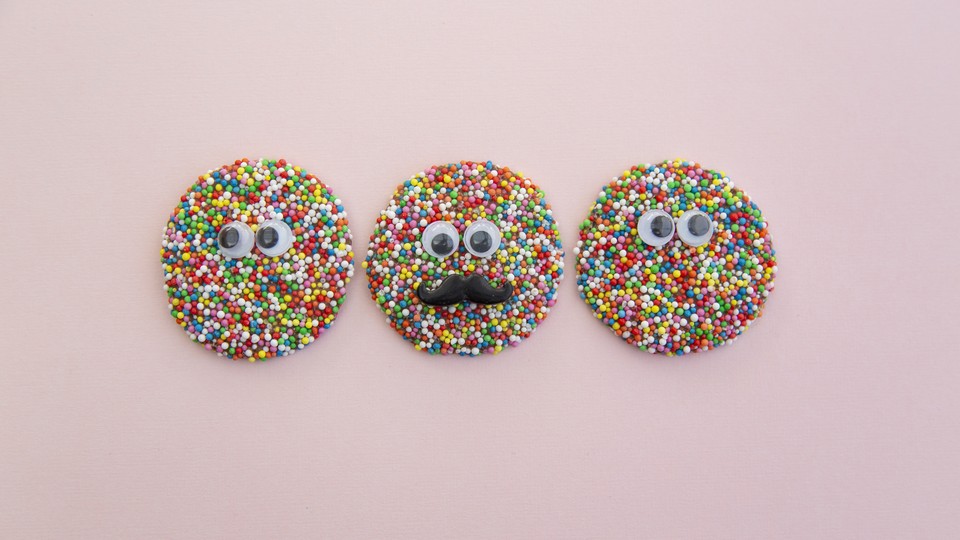 Three sprinkled cookies with plastic googly eyes on them
