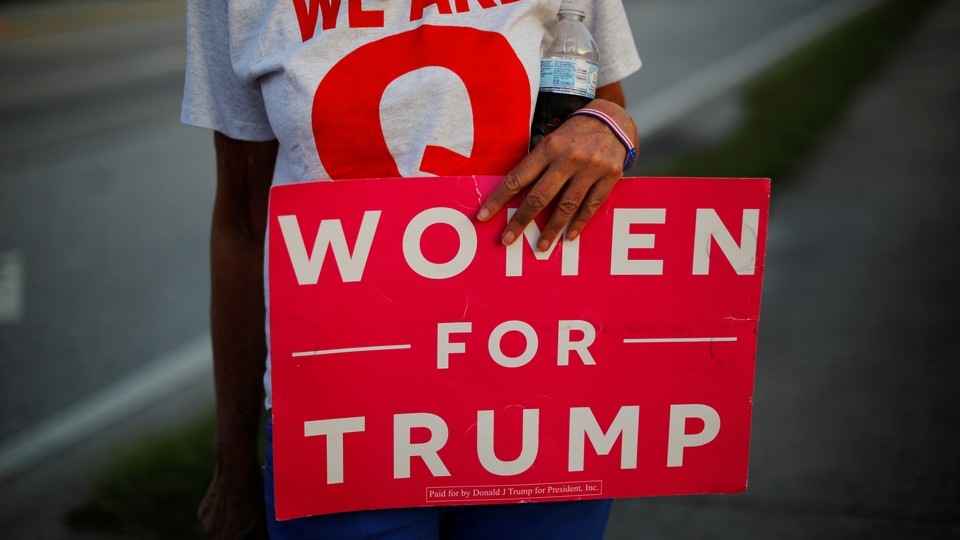 A woman holding a "Woman for Trump" sign.