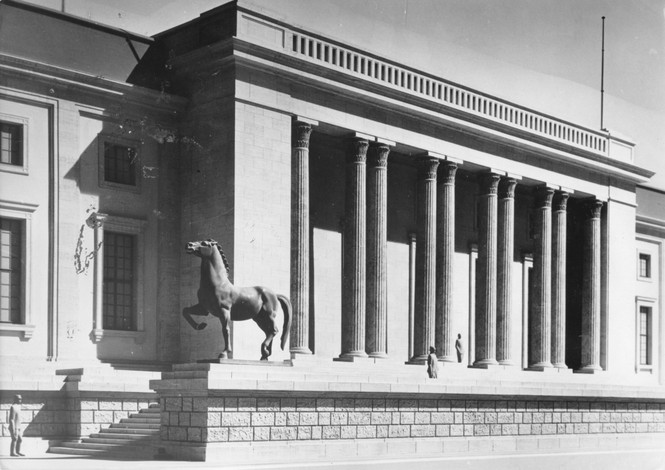 A large horse sculpture in front of a building artifice with columns