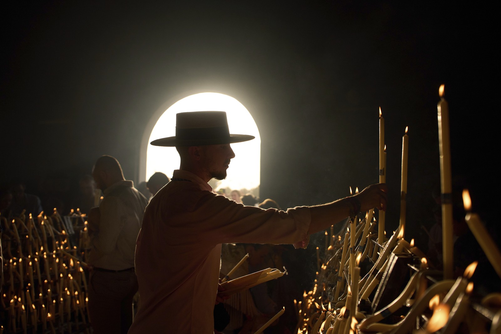 People inside a dark shrine light and place candles.