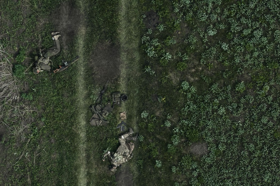 A drone's-eye view of the bodies of two Russian soldiers lying in a field, along tire tracks