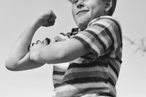 a young boy flexing a muscle in black and white