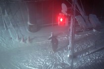 A person stands on a street corner at night in the snow.