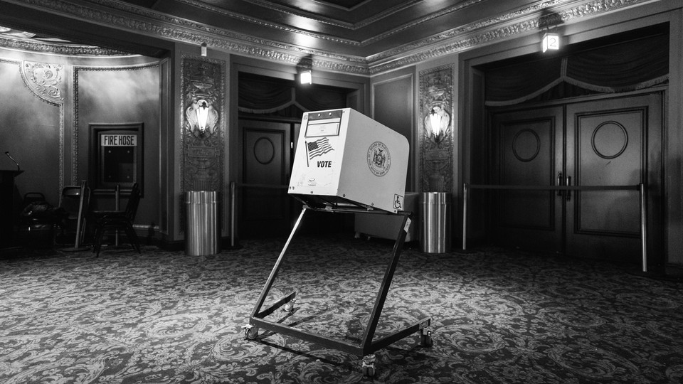 A black-and-white photo of a voting booth in what looks like an ornate theater