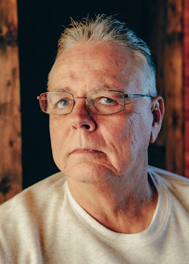 color portrait of man with glasses and graying hair against wood background