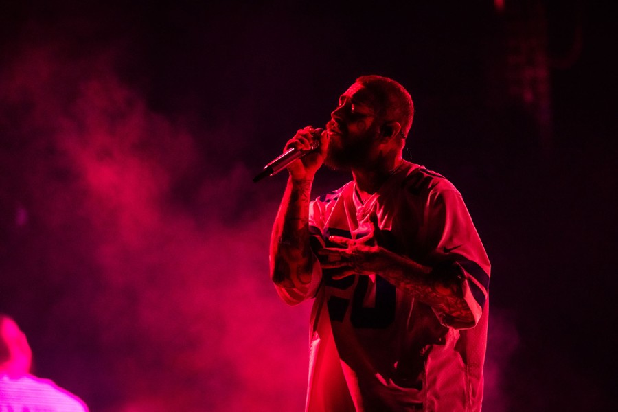 A bearded, tattooed man sings into a microphone onstage.