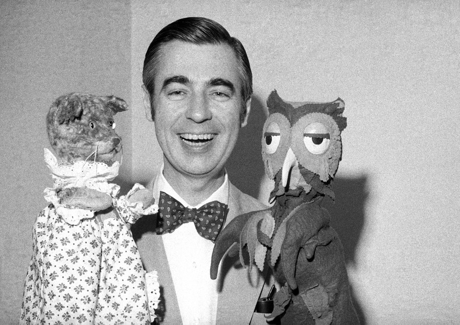 Mr. Rogers holds up puppets Henrietta Pussycat and X the Owl.