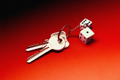 two keys attached to a keychain with two dice on it, against an ominous red background