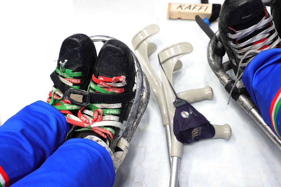 A close view of booted feet strapped into an ice hockey sled.