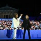 Oprah Winfrey and Kamala Harris hold hands in front of a crowd