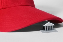 A red MAGA cap’s brim hovering over a courthouse