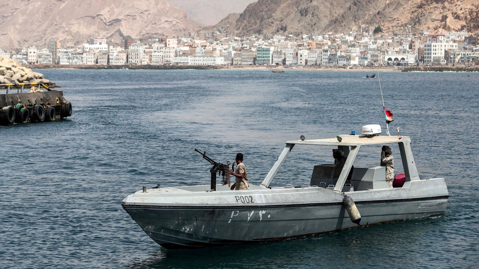 A boat with a Yemeni soldier manning a weapon patrols the coast of the port city Mukalla.