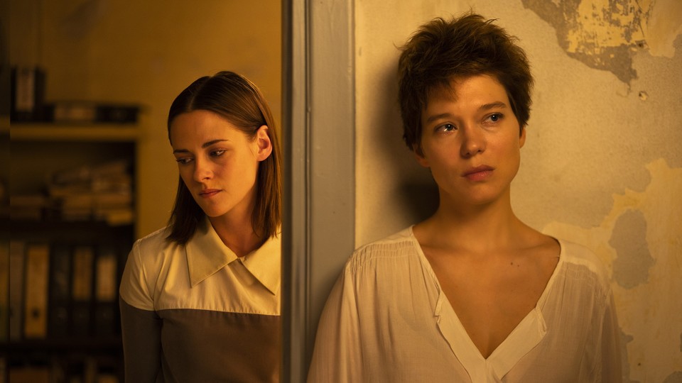Kristen Stewart and Léa Seydoux standing solemnly by a doorway in "Crimes of the Future"