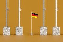 A small german flag in a line of tall flagpoles
