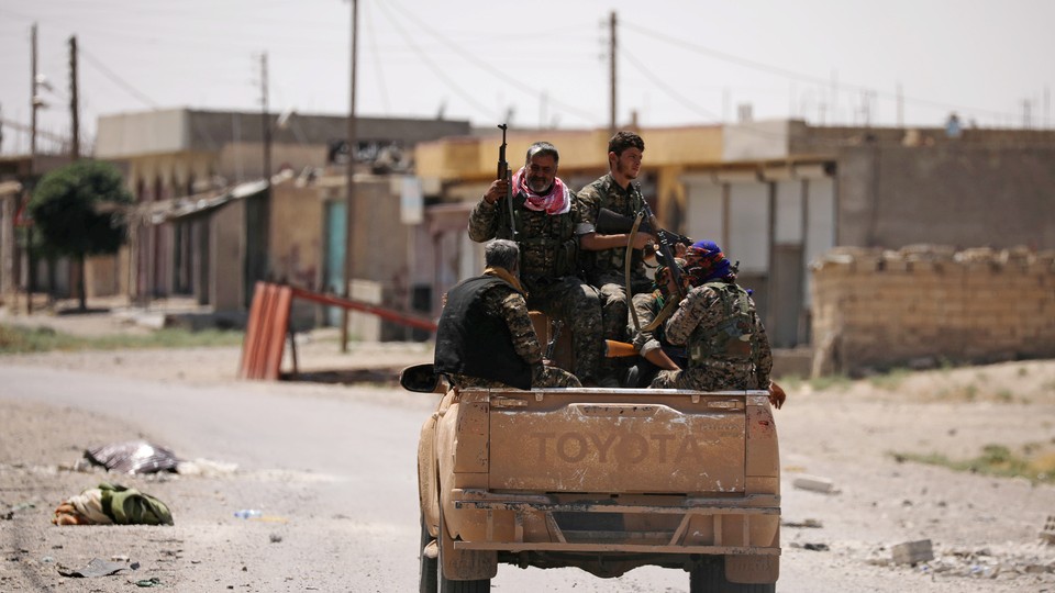 Syrian Democratic Forces (SDF) ride on a pick-up truck in Raqqa's western neighbourhood of Jazra on June 11, 2017. 