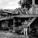 A woman in Puerto Rico stands beside a devastated home.