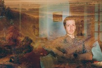 photo with a double exposure, one of a man sitting in his living room next to a guitar with a hazy overlay of a 17th-century landscape painting