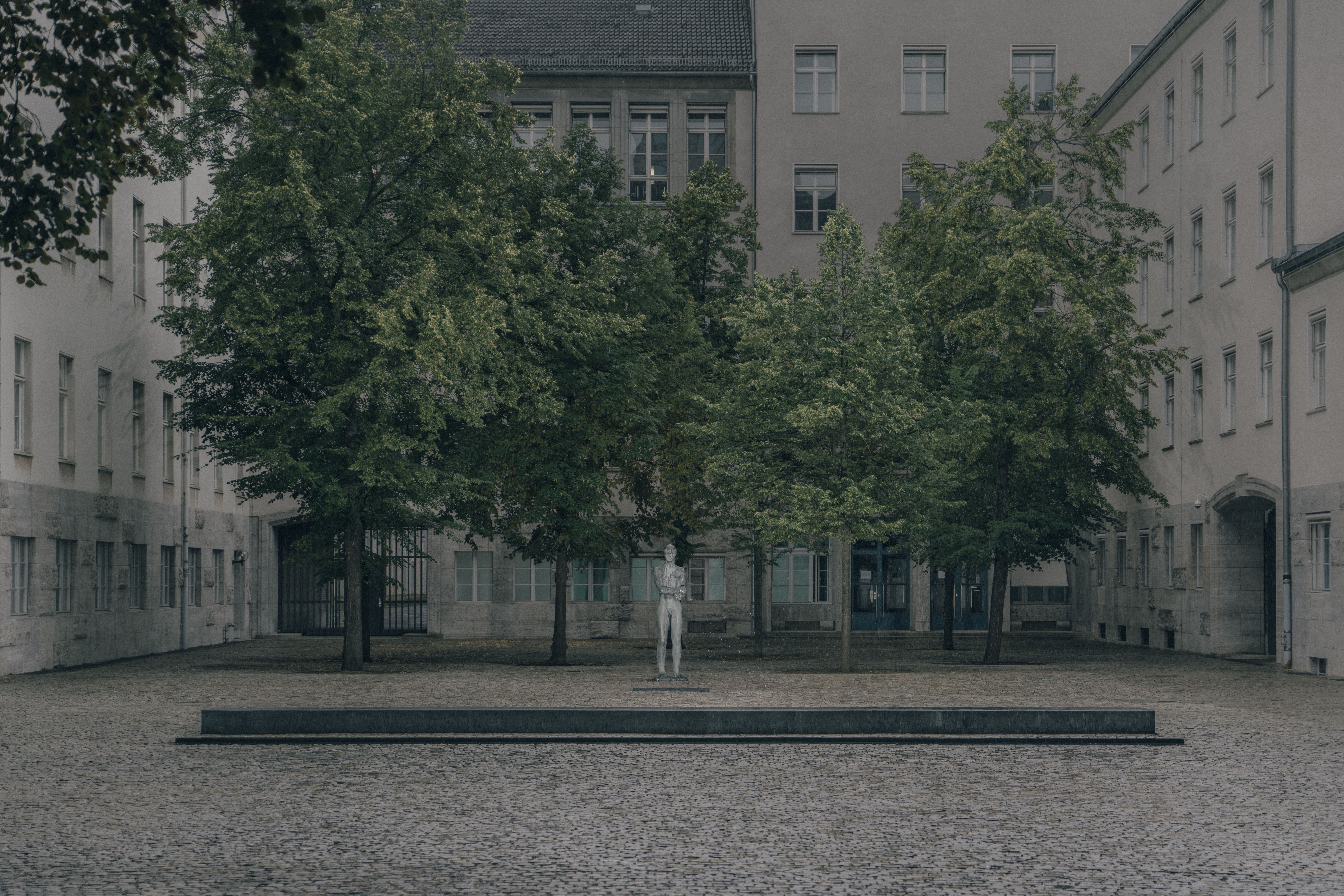 photo of a statue in an austere courtyard with trees 