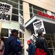 Hotel workers march and hold picket signs in front of a Marriott hotel.