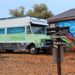 A green and blue food truck parked outside a colorful building