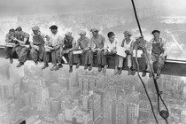 A group of steel workers eats lunch on a beam hundreds of feet above New York City.