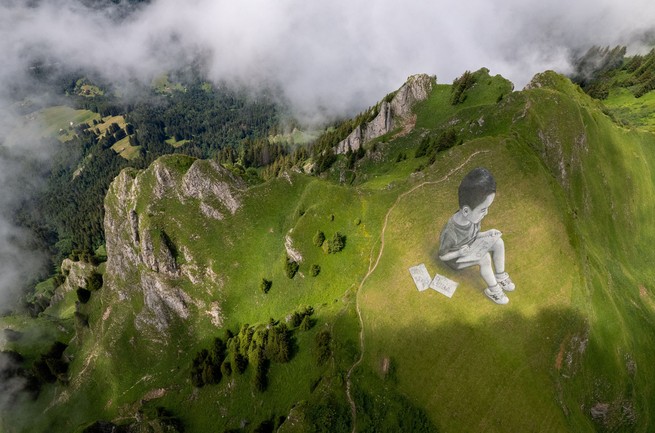 A land-art painting that depicts a child drawing, created by the Swiss French artist Saype