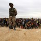 A Jordanian soldier stands guard as Syrian refugees, stuck between the Jordanian and Syrian borders, watch a group of them cross into Jordanian territory.