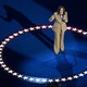 Kamala Harris speaking to microphone, standing in the middle of a circle of stars