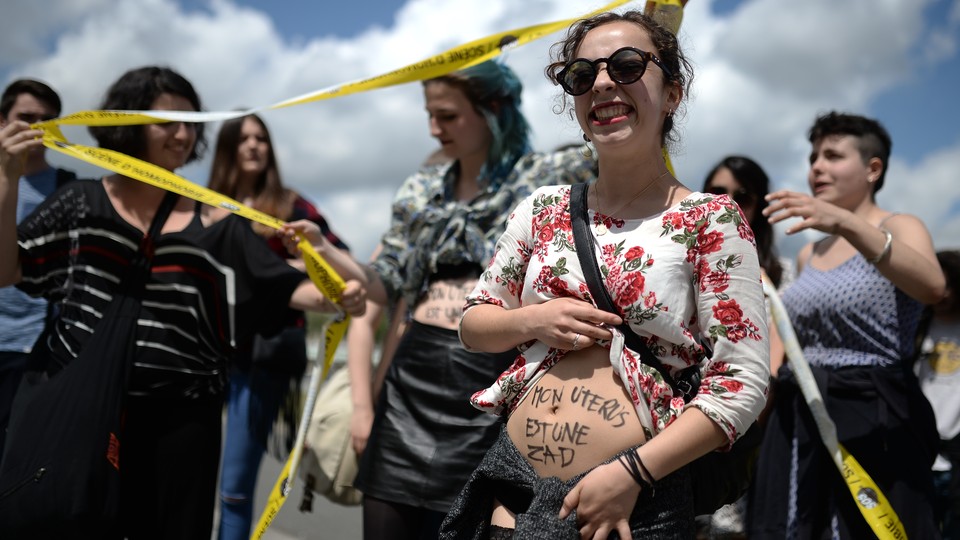 A woman shows writing reading 'my uterus is a ZAD (zone to defend)' as protesters face supporters of the anti-gay marriage La Manif Pour Tous (Protest for Everyone) movement during a protest against medically assisted procreation techniques for lesbian couples and surrogacy on May 10, 2016 in Nantes, western France. 