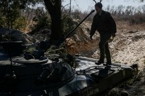 A Ukrainian fighter steps onto a tank.