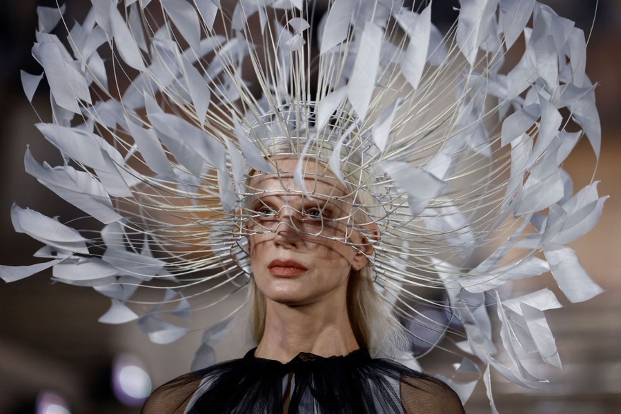 A model wears an elaborate head covering, made of wire and many strips of fabric.