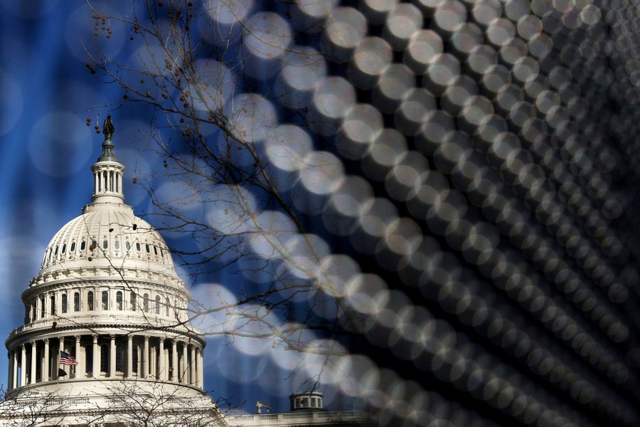 A view of the U.S. Capitol building, seen through a fence.