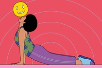 A woman in the upward-dog yoga pose balancing a smiley face on her nose